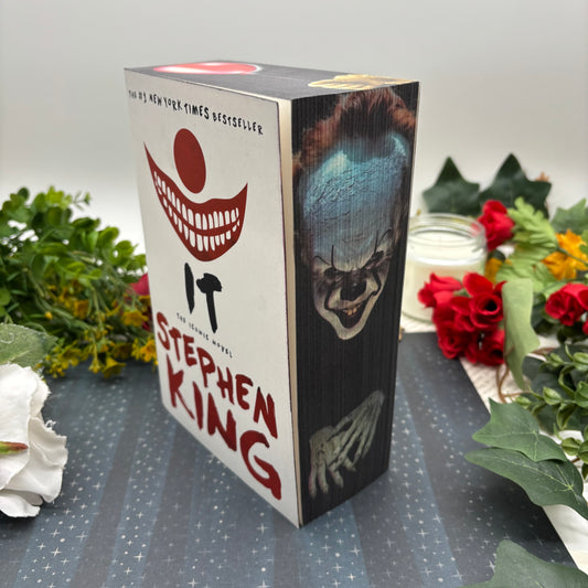  'IT' by Stephen King with a clown illustration on a decorative surface with flowers.
